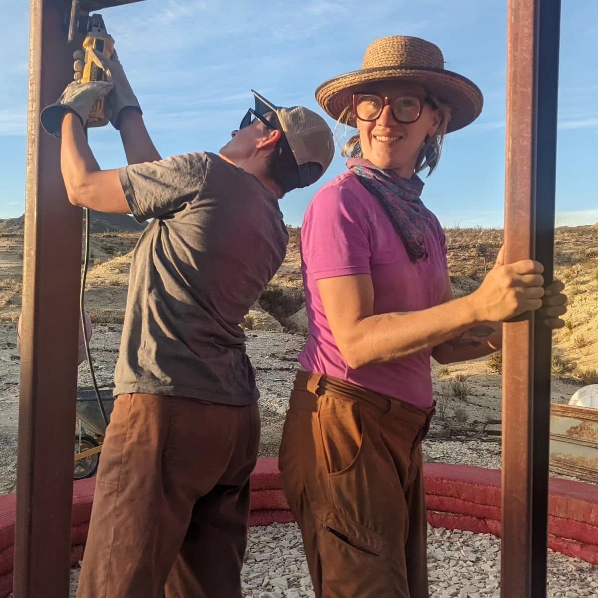 Two Co-Lab participants raising a timber frame at a hyperadobe community build
