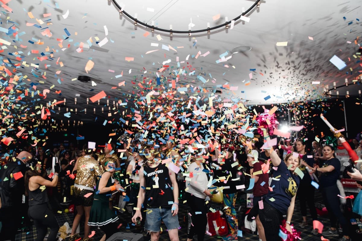 Confetti filling the air over a crowd dancing at an indoor event